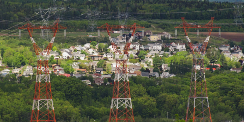 Three orange and white metal towers set against a rural town backdrop.